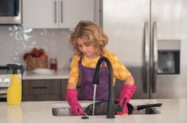 Tabak yıkama konsepti. Evde çocuk temizliği, konsept büyüme, gelişim, aile ilişkileri. Çocuk hizmetçisi bulaşıkları sabunlu suyla yıkıyor.