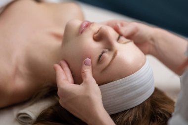 Yüz maskeli kadın. Kozmetik prosedürü. Güzellik kaplıcası ve kozmetoloji. Güzellik tedavileri. SPA salonunda yüz gerdirme. Kozmetik uzmanı kız yüz masajı yapıyor. Kozmetik prosedürü. Güzellik kozmetolojisi