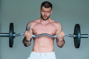 Spor salonunda poz veren kaslı iri kıyım. Spor aletlerinin yanında fitness mankeni. Genç kaslı adam egzersizi. Spor salonundaki güçlü kaslı adam. Spor ve motivasyon. Ağırlıkla egzersiz yapar