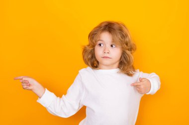 Sarı izole edilmiş stüdyo geçmişini işaret eden şaşkın çocuk. Şok olmuş bir çocuk, reklam teklifleri sunuyor.