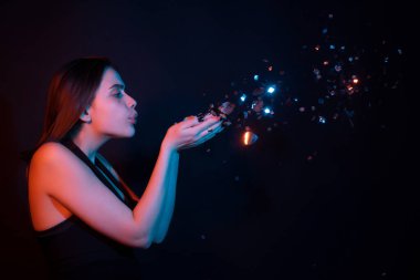 Doğum günün kutlu olsun. Konfeti üfleyen güzel bir kadının stüdyo portresi. Doğum gününde ya da sevgilisinde güzel bir kızın portresi. Seksi model doğum gününde ışıldıyor. Doğum gününü kutlayan şehvetli kadın.