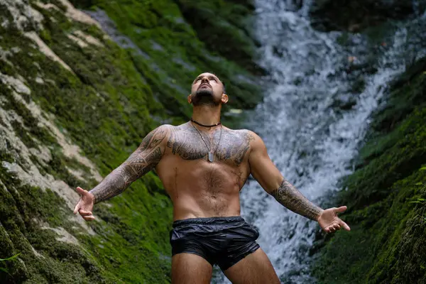 Doğada meditasyon ve sağlık. Çevrede erkek özgürlüğü. Ormanda şelaleye karşı meditasyon yapan rahat bir adam. Özgürlük ve kaygısız yaşam tarzı. Doğa konseptinde seyahat ve turizm