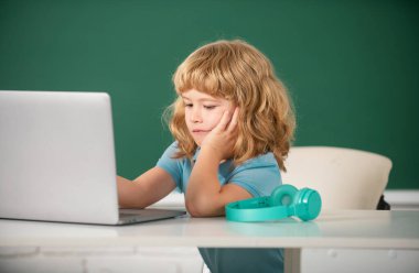 Okulda dizüstü bilgisayar kullanan çocuk. Eğitim, okul, teknoloji ve çocuk kavramı