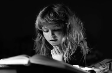 Çocuk uyumadan önce yatakta kitap okuyor. Evdeki küçük çocuk yatakta uzanıp kitap okuyor. Çocukların hayal gücünün gelişimi.