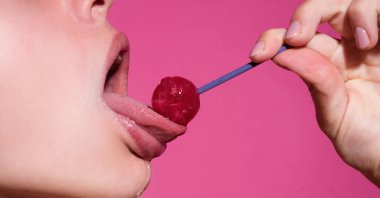 Lolipop yalayan bir kadın, sanat afişi, lolipoplu kırmızı dudaklar. Lolli pop ile seksi kırmızı kadın ağzı ve dili. Pembe üzerine izole edilmiş tasarım için resim baskısı