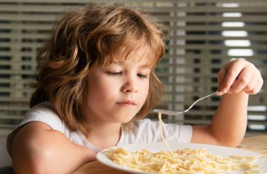 Makarna yiyen küçük bir çocuğun portresi, spagetti. Çocuk kavramı yakın planda. Kafa vuruşu çocuk portresi