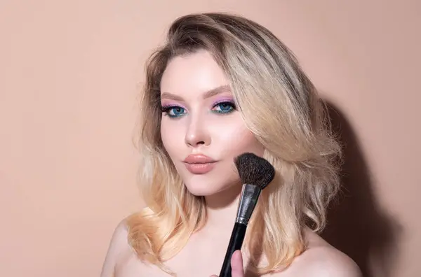 stock image Beautiful young woman with makeup blusher brush. Facial treatment. Cosmetology, beauty and spa. Portrait of beauty model with make up on beauty face