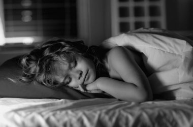 Çocuk geceleri yatakta uyuyor. Çocuk evde yatakta uyuyor. Yatma vakti, çocuk uyuyor. Çocuk battaniyeli yumuşak yastıkta uyuyor.