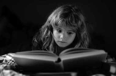 Çocuk yatakta sihirli bir kitap okuyor. Çocuk evde kitap okurdu. Çocuğun gelişimi. Akıllı çocuk.