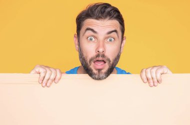 Bilgi konsepti. Boş levhalı şaşırmış bir adam. Metin veya tasarım için kopyalama alanı gösteriliyor. Heyecanlı adam stüdyo arka planında boş reklam panosu gösteriyor. Reklam için boş pankart