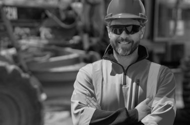 Kasklı bir inşaat işçisi. Yeni bina inşaatında çalışan bir işçi. İnşaat alanında çalışan bir inşaat işçisi. Foreman işçi portresi. Miğferli açık hava portresi. Sıkı şapkalı bir işçi