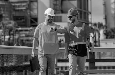 Endüstriyel işçiler dışarıda. Güvenlik üniformalı mühendisler ve kasklar dışarıda fabrikada. Fabrika işçisi sanayi mühendisleri. Fabrika sanayi mühendisleri dışarıda yürüyor.