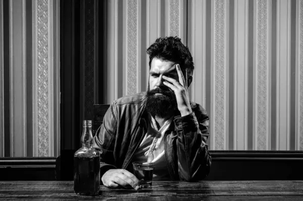 stock image Bearded brutal hipster man drinking expensive cognac. Serious problems with alcohol addiction. Alcoholism treatment. Handsome man drinking alone