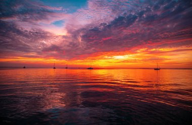 Gün batımı sahili. Deniz yüzeyinin altında büyük sarı güneşli parlak gün batımı