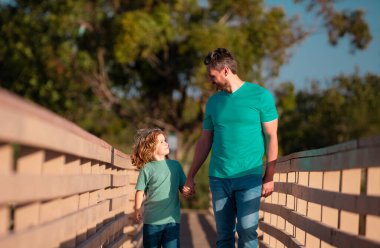 Baba oğul ağaçlık köprüde yürüyorlar.
