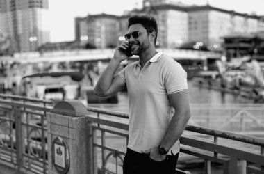 Sokakta telefonla konuşan bir adam. Dışarıda kendine güvenen yakışıklı bir adam telefonda konuşuyor. İş telefonu konuşması. Moda adamı, Amerikan şehrinin arka planında telefon kullanıyor.