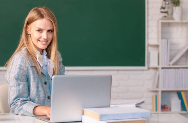 Lise öğrencisi masada oturuyor ve deftere yazıyor, sınıfta İngilizce ya da matematik öğreniyor.