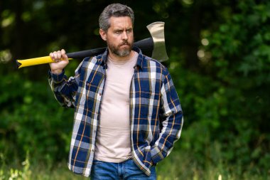 Ormanda baltası olan çalışkan bir adam. Büyük baltası olan sakallı bir oduncu. Ekose gömlekli vahşi sakallı bir adamın portresi bir balta tutuyor. Erkek güzelliği ve erkeklik