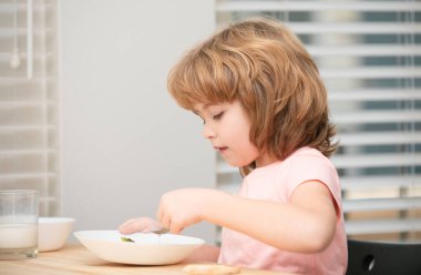 Tatlı bir çocuğun portresi çorba yiyor ya da kahvaltısını evde kaşıkla yemek yiyor. Çocuklar sağlıklı yiyecekler