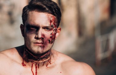Kafatası genç adamın portresini yapar. Çıplak adam ürpertici oyulmuş halloween balkabağı tutan. Zombi makyajlı bir adamın yakın çekim portresi. Kafa yaralanması ile Kanlı çıplak adam, kanlı tema, cadılar bayramı teması