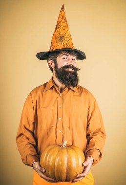 Cadılar Bayramı şapkalı korkunç hippi adam. Cadılar Bayramın kutlu olsun yakışıklı adam. Şükran Günü 'nü kutluyoruz. Cadılar Bayramı şapkalı yakışıklı adam balkabağı tutuyor - yakın plan portre