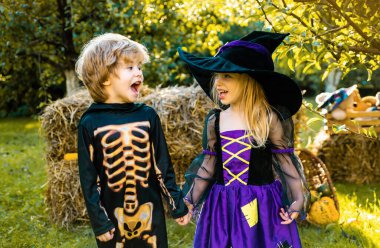 Cadılar Bayramı çocuk tatil konsepti. Cadılar Bayramı kostümleri giyen çocuklarla Cadılar Bayramı partisi. Iskelet ve cadı kostümü tutan ve şeker yeme ile Mutlu çocuklar. Trick-or-treat çocuk kavramı