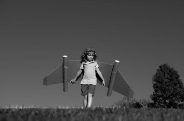 Çocuk hayal gücü, pilotluk hayali ve jet kanatları üzerinde uçmak. Oyuncak jetpack ile oynayan mutlu çocuk. Çocuk pilot yeşil çimlerde eğleniyor. Başarı, çocukların yeniliği ve lider konsepti