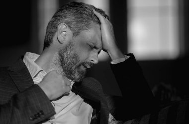 Baş ağrısı, yorgunluk ve stres. Takım elbiseli adamın yakın plan portresi baş ağrısı yapıyor. Baş ağrısı konsepti. Ofiste acılı adamlar streslidir. Stresli ve baş ağrısı