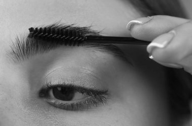 Kaşlar şekilli. Kadının kaş makyajı yaptırmasına yakın çekim. Makro kaşına fırçayla kozmetik uyguluyordu. Mükemmel bir kaş şekli, kahverengi göz farı ve uzun kirpikleri. Şekli kaşlar