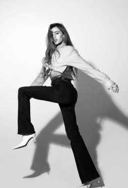 Hareket modeli. Pembe gömlekli ve kot pantolonlu moda kadını. Moda pozu vermiş güzel bir bayan, uzun boylu.