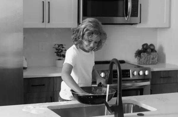 stock image Home chores. Kid in kitchen cleaning plates. Cute boy washing dishes in domestic kitchen. Child boy washing the dishes in the kitchen sink