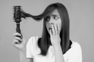 Üzgün kadın saçının zarar görmesine, saç dökülmesine bakıyor. Stüdyo izole edilmiş portre, kopyalama alanı