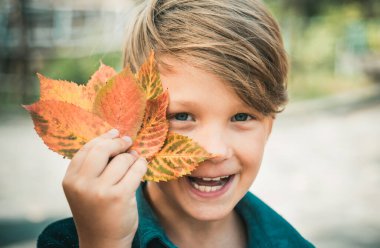 Yaprakları ile oynama ve kameraya arıyorum küçük boy gülümseyerek. Yakın çekim portre. Çocuk çocuk saman üzerinde yatıyor. Çiftlik köyü zemin üzerine altın varak tutan şirin küçük çocuk çocuk
