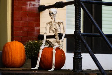 Cadılar Bayramı süslemeleri. Cadılar Bayramı balkabağı ve dekore edilmiş ev için iskelet. Bir Amerikan evinin ön bahçesinde dekore edilmiş korkunç bir şey. Şeker mi şaka mı? Cadılar Bayramı geçmişi. Cadılar Bayramı 'nın sonbahar tatili