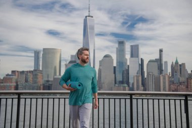 Spor salonundaki son sınıf öğrencisi Manhattan yakınlarında egzersiz yapıyor. Sağlıklı bir emeklilik hayatı. Aktif kıdemli adam dışarıda egzersiz yapıyor. Emeklilikten sonra aktif. Olgun emekli sporcu esneme egzersizleri yapıyor.