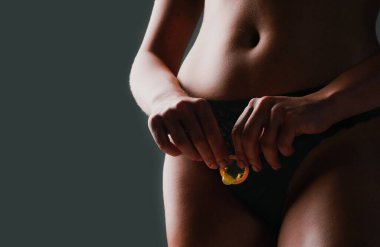 Cinsel yolla bulaşmasını önlemek için prezervatif. Güvenli seks için prezervatif. Seksi manken prezervatifi seksi çıplak vücutta tutuyor. Kesilmiş, prezervatifli seksi kadın. Güvenli seks konsepti. Prezervatifle sevişmek.