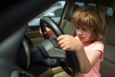 Şoför çocuk. Araba kullanıyormuş gibi yapan sevimli bir çocuk. Çocuk arabada, elleri direksiyonda. Çocuk Sürücüsü. Küçük çocuk araba kullanıyor. Direksiyonda oturan çocuk. Rüya, hayal gücü, çocukluk