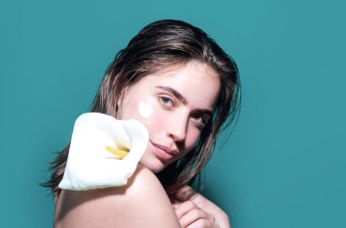 Stüdyo arka planına izole edilmiş yüz kremi süren güzel, yarı çıplak bir kadının portresi. Cilt bakım ürünü. Yüzünde nemlendirici krem var. Mükemmel cilt, sabah rutini