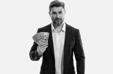 İyi ödeme. Yakışıklı bir iş adamı, gri stüdyoda izole edilmiş para tutuyor. Dolar banknotları halinde para. Yığınla para, finans, yatırım ve tasarruf