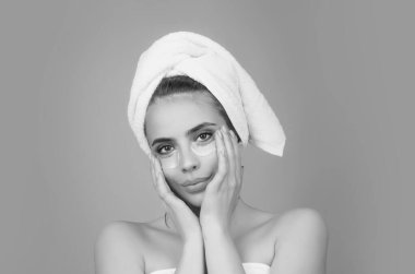 Göz bantları, göz altı bantları. Kafasında havlu olan genç bir kadın cilt için yüz bandı kullanıyor. Göz tedavisi. Kozmetik yamalar jel. Yüzünde hidrojel göz bandı, cilt bakımı