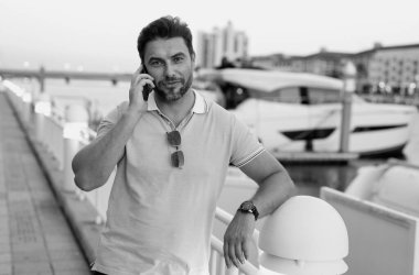 Şehir caddesinde telefonda konuşan yakışıklı bir adam. Büyük şehirde şehir hayatı yaşayan başarılı bir erkek model telefonda konuşuyor. Genç erkek manken dışarıda telefon kullanıyor. İş telefonu görüşmesi