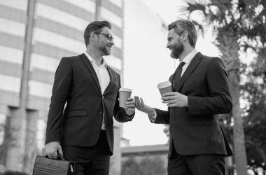İş iletişimi. İki iş adamı dışarıda kahve molası veriyor. İki farklı iş adamı birlikte konuşuyor. İş arkadaşları projeyi tartışıyor ve düşünüyor. İki iş adamı arasında konuşmak.