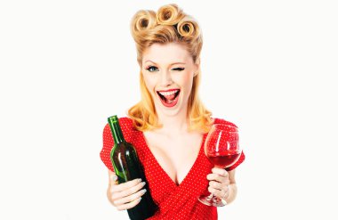 Elinde bir kadeh kırmızı şarap tutan gülümseyen genç bir kadının portresi. Kırmızı elbiseli güzel sarışın kadın kırmızı şarap içiyor. Kırmızı dudaklar makyaj malzemesi.