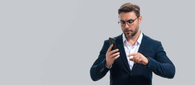 Takım elbiseli yakışıklı bir adamın portresi akıllı telefon kullanıyor, sohbet ediyor, sosyal medyada mesaj yazıyor. Telefondaki iş adamı araması stüdyo geçmişinden izole edilmiş. Başlık için pankart, kopyalama alanı