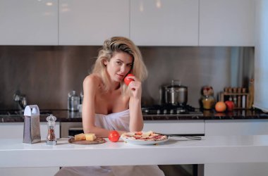 Pizza, peynir, sosis ve domates malzemeleri olan kadın. Mutfakta kahvaltı yapan seksi kadın. Seksi pijama giyen kadın evde kahvaltı yapıyor.