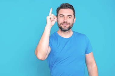 Gülümseyen adam stüdyo arka planında bir fikir düşünüyor. İnsan portresinin birçok fikri vardır. İşaret parmağı olan bir adamın tanıtım teklifi sunacak bir fikri var. Karar verme süreci. İyi fikir.