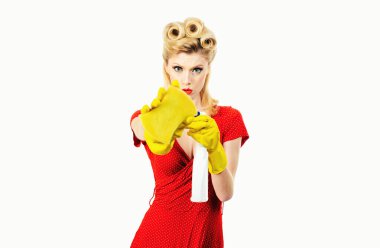 Güzel, genç bir kadın bir bez parçası tutuyor ve camları yıkamak için sprey sıkıyor. Beyaz bir arka planda izole edilmiş. Elleri eldivenli temizlikçi kadın.