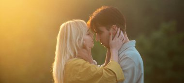 Sarılıp kucaklaşan genç aşıklar. Şehvetli aşıklar gün batımında sarılıp öpüşüyorlar. Sevgi ve şefkat dolu bir çift.