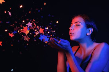 Konfeti üfleyen seksi kız. Doğum gününde, sevgililer gününde güzel bir genç kadının portresi. Seksi kız doğum gününde ışıltı saçar. Doğum gününü kutlayan şehvetli kadın. Sevgililer günün kutlu olsun. Doğum günü partisi