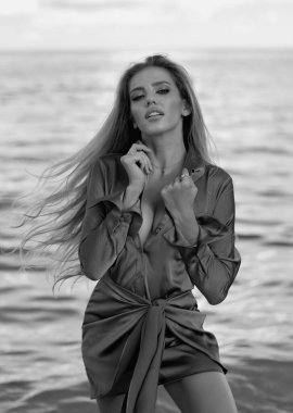 Açık havada poz veren seksi modelin portresi. Yaz kumsalında şehvetli bir kadın poz veriyor. Mavi yaz elbisesi giymiş romantik genç bir kadın. Doğal seksi memeler, kadın vücudu, seksi göğüsler. Sütyen modeli